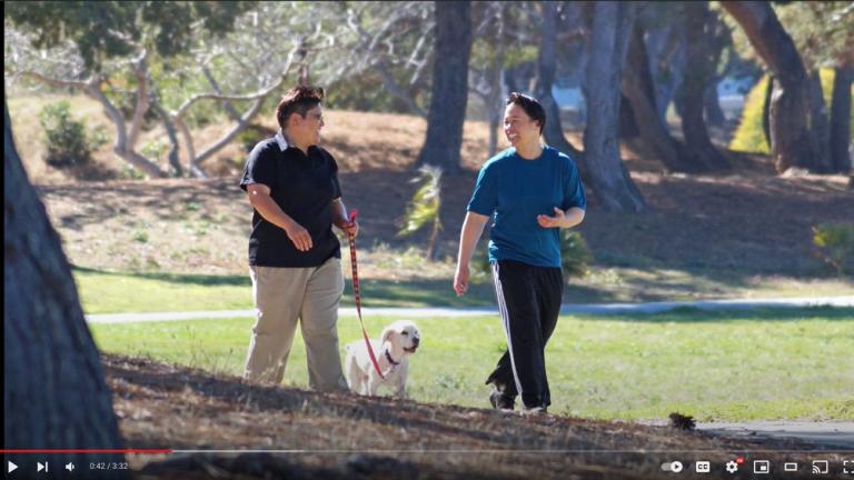 couple walking dog in the park